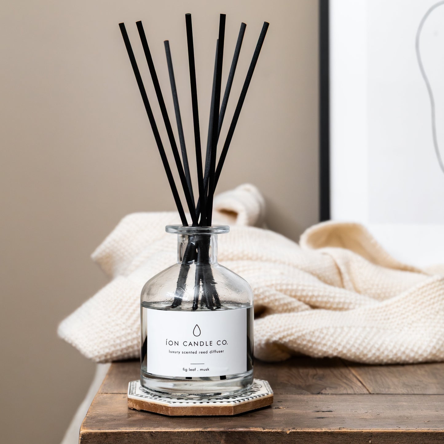 Diffuser with black sticks on a wooden surface with a beige background