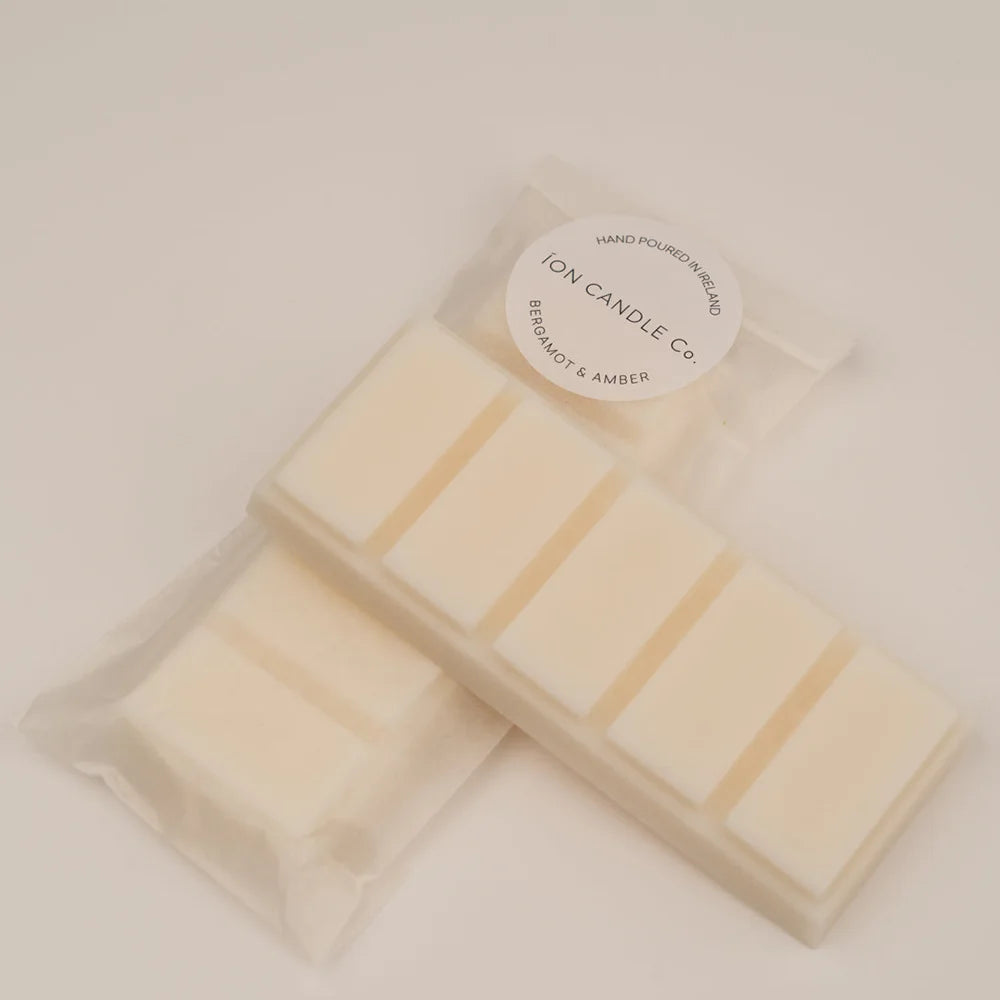 Ion Candle Co. - Luxury scented bergamot & amber wax melts in their clear plastic packaging against a beige background