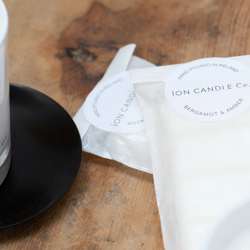 Ion Candle Co. - Luxury scented bergamot & amber wax melts in their white paper packaging against a wooden background