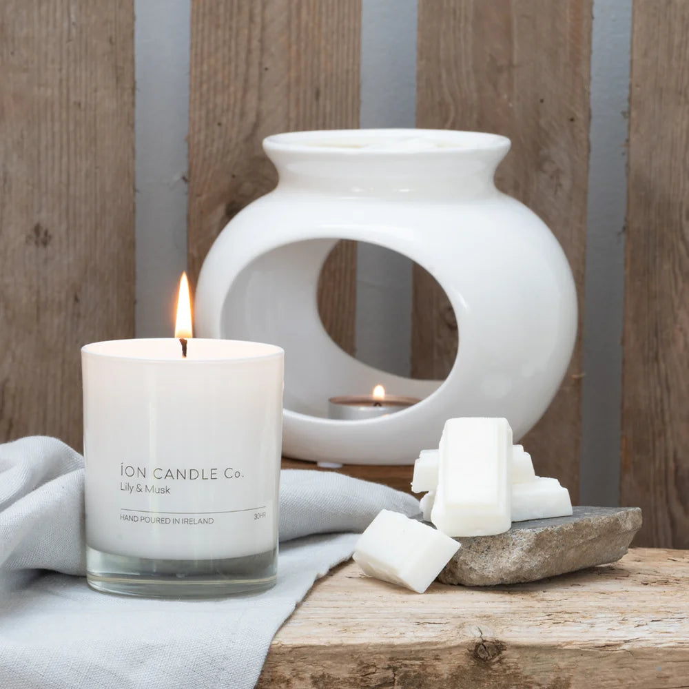 Ion Candle Co. - White Ceramic Wax Melt Burner, with scented candle beside it, against a wooden wall background.