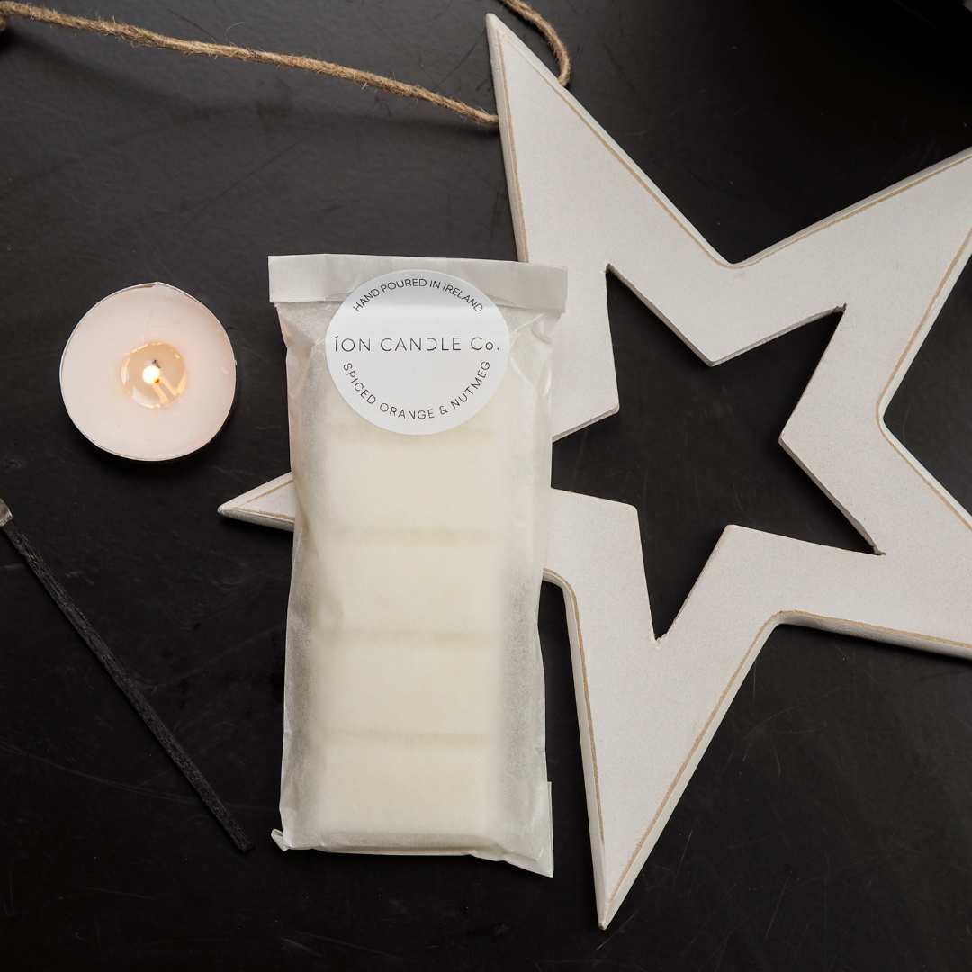 luxury christmas scented wax melt Spiced ornage & nutmeg on a black flat surface with tea light and white star