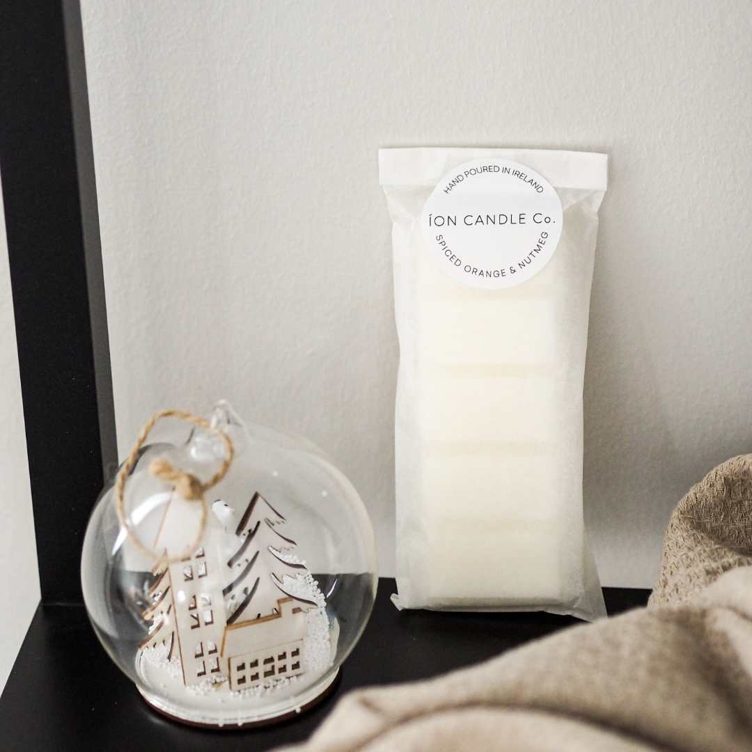 luxury christmas scented wax melt Spiced ornage & nutmeg with a white back drop with christmas bauble and soft cotton throw