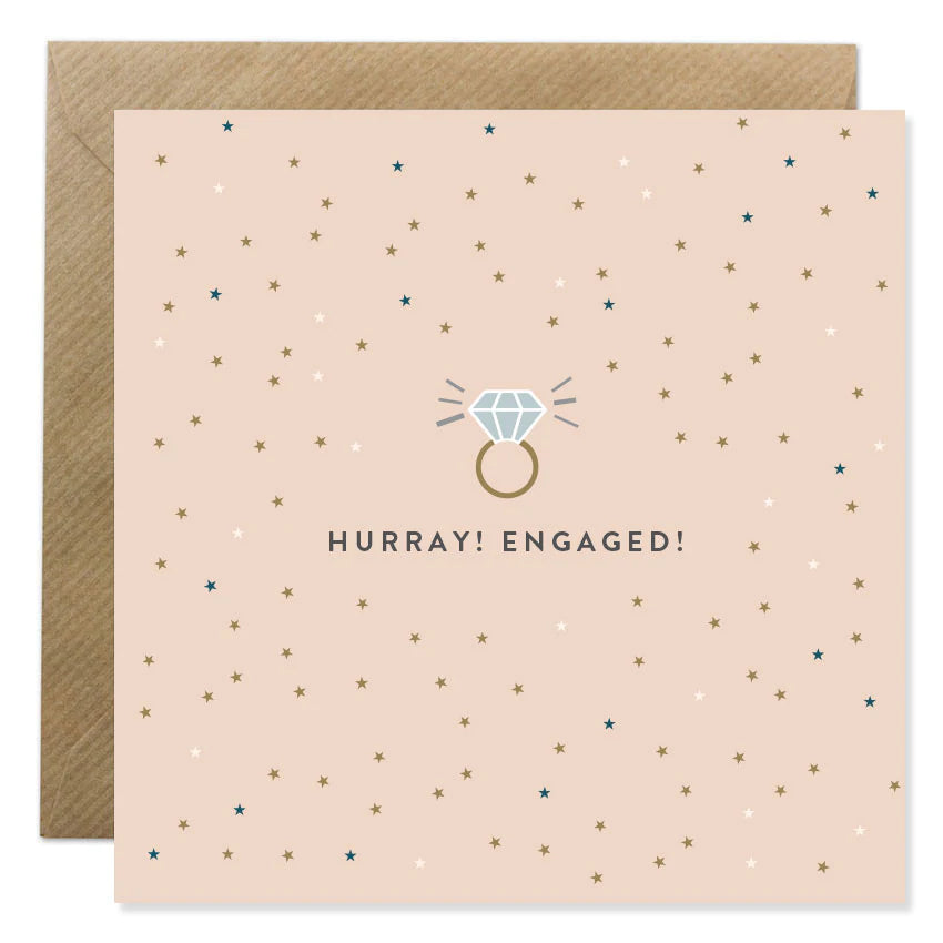 Ion Candle Co. - Engagement Greeting Card. The card is blush pink with various coloured dots scattered around text which is in the centre and reads 'Hurray! Engaged!' Above the text is an image of a sparkling diamond ring