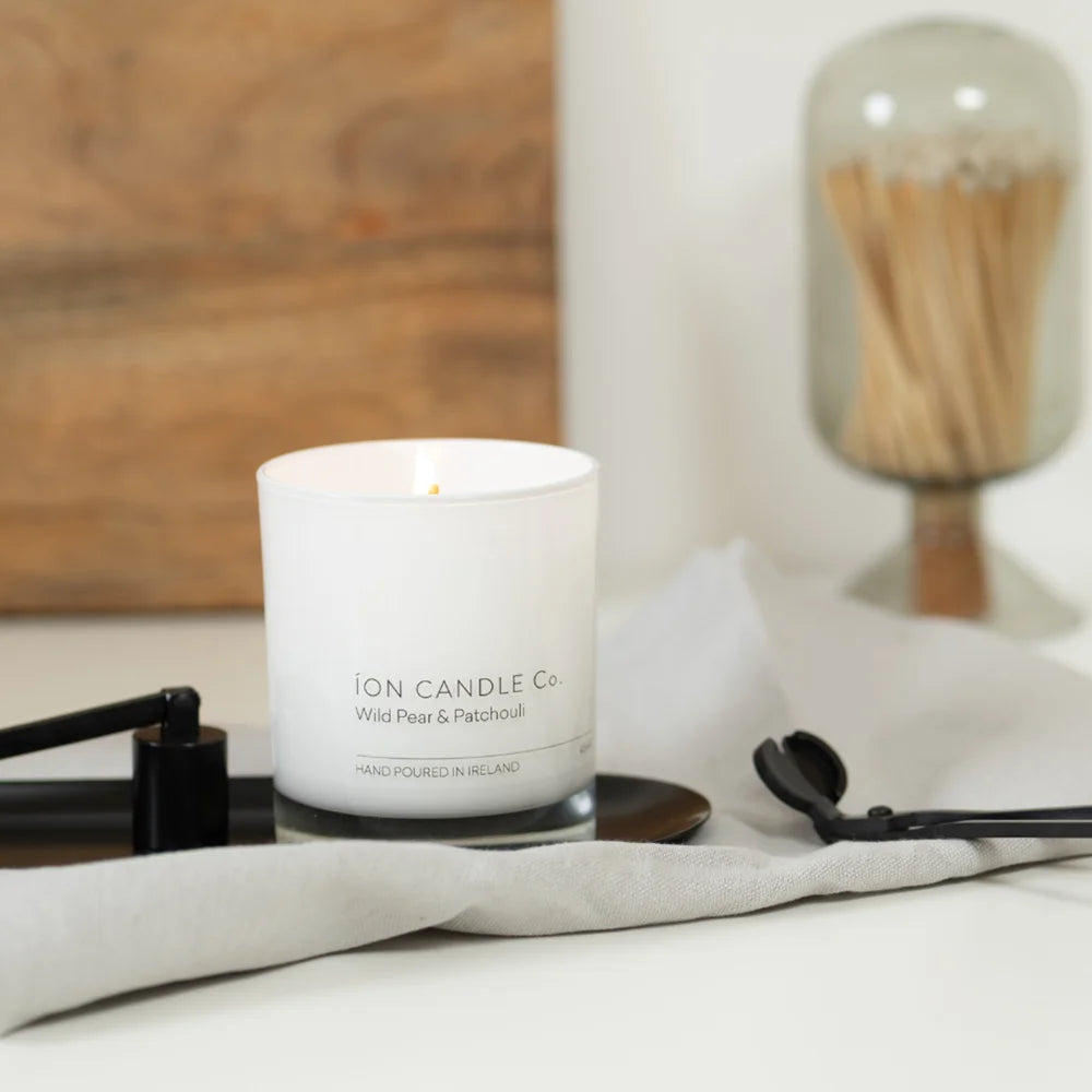 Ion Candle Co. - 3 Piece Candle Tool Set on a white background. Includes case, wick trimmer and snuffer tools all in black. The tools are laid out beside a Wild Pear & patchouli scented candle