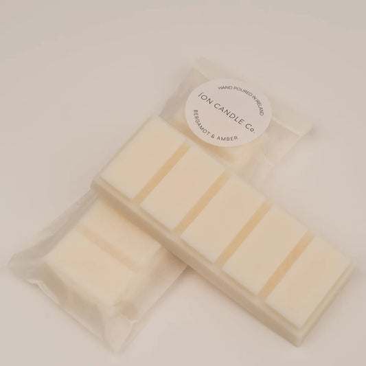 Ion Candle Co. - Luxury scented bergamot & amber wax melts in their clear plastic packaging against a beige background