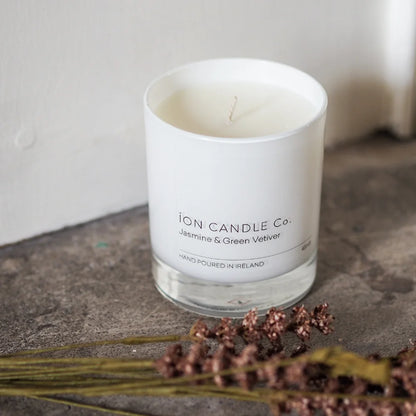 Ion Candle Co. - Jasmine & Green Vetiver Luxury scented candle on a stone worktop with some wild grasses placed in the foreground