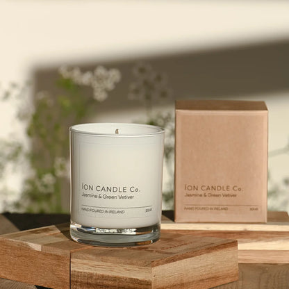 Ion Candle Co. - Jasmine & Green Vetiver Luxury scented candle on a wooden block against a floral background