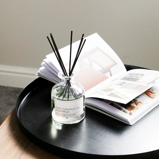 Ion Candle Co. - Lily and Musk Scented Reed Diffuser placed on a black serving tray next to an open book