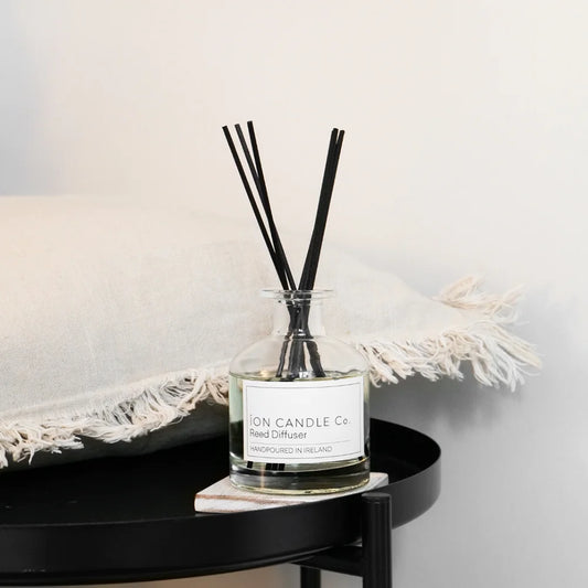 Ion Candle Co. - Luxury Reed Diffuser Neroli & Orange Blossom. Placed on a circular black coffee table with a white cushion next to it.
