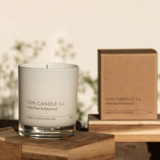 Ion Candle Co. - Luxury Scented Wild Pear and Patchouli Candle on a small wooden block against a floral background