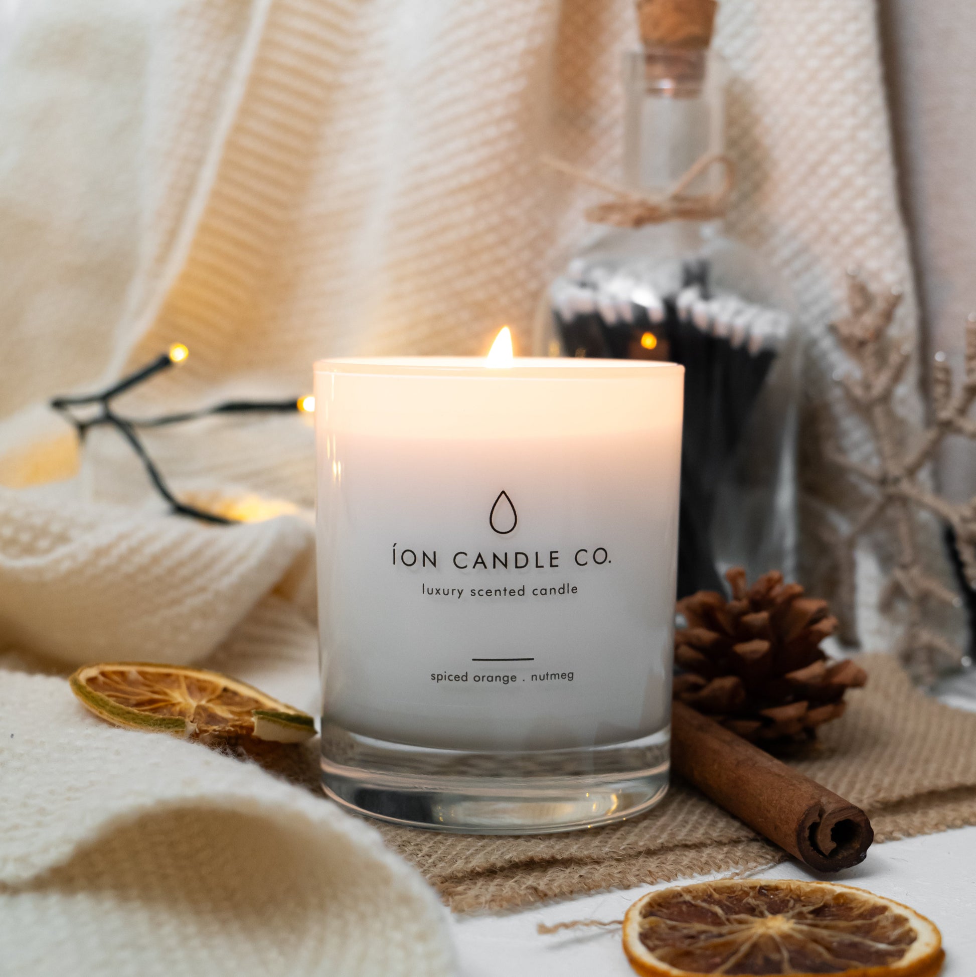 Candle from Ion Candle Co with decorative elements on a soft fabric background