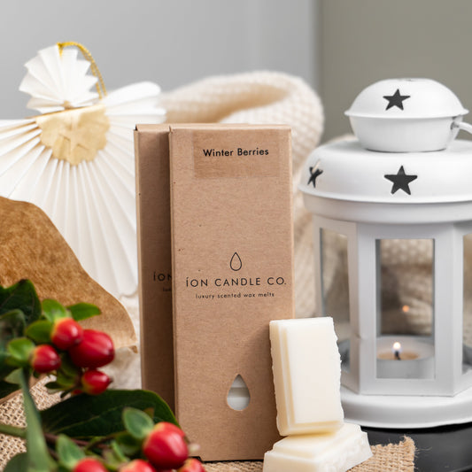 ION Candle Co product on a table with winter berries and a white lantern.