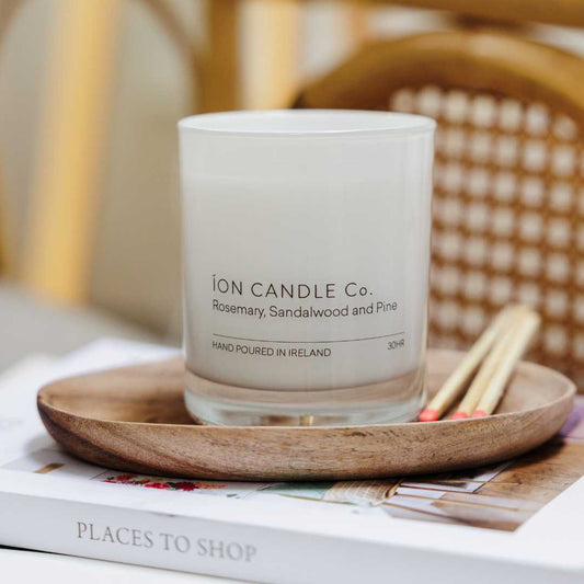 Ion Candle Co. - Rosemary, Sandalwood & Pine luxury scented candle sitting on a wooden board with matches and books displayed 