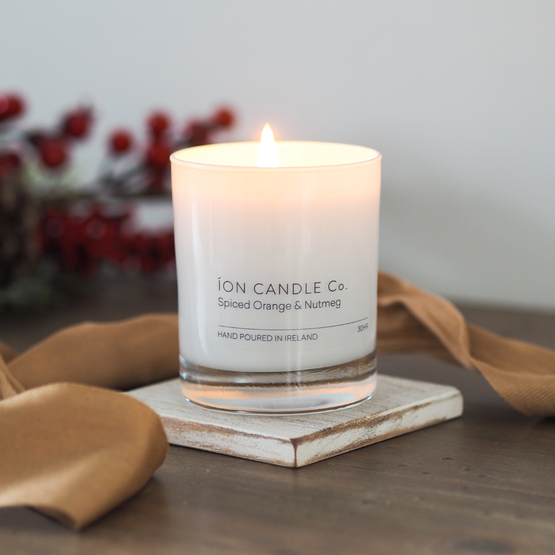 Spiced orange and nutmeg christmas luxury candle. Luxury pumpkin spiced scented candle lighting with caramel ribbon draped across 